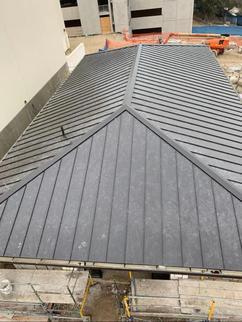 Commercial metal roof construction with crane equipment in Alvin